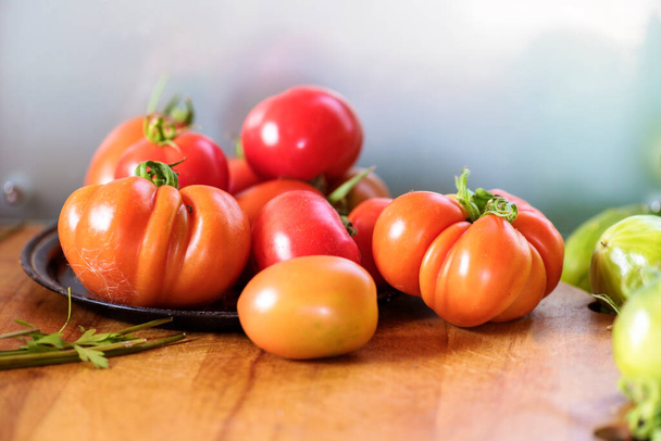 Κόκκινες ώριμες ντομάτες από τον κήπο, στο τραπέζι της κουζίνας - Φωτογραφία, εικόνα