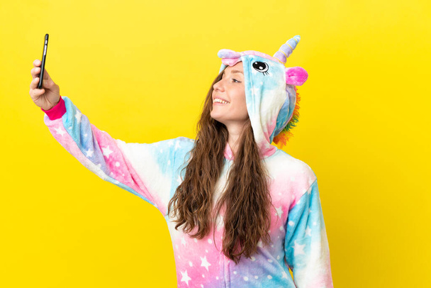 Κορίτσι με πιτζάμες μονόκερω πάνω από απομονωμένη φόντο κάνει μια selfie - Φωτογραφία, εικόνα