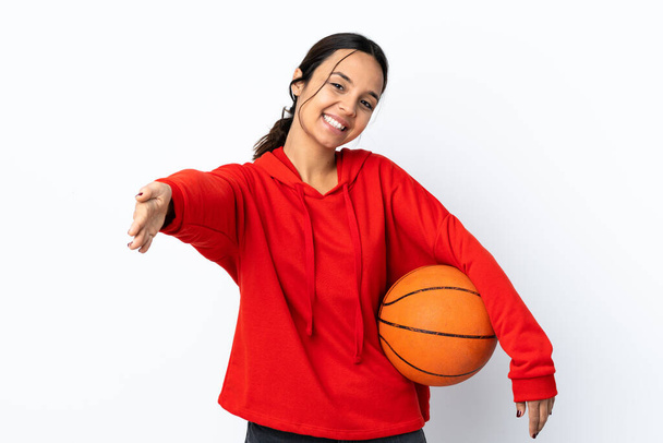 İzole edilmiş beyaz arka planda basketbol oynayan genç bir kadın sunar ve davet eder. - Fotoğraf, Görsel