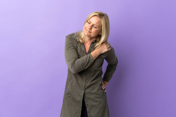 Middle age Lithuanian woman isolated on purple background suffering from pain in shoulder for having made an effort - Foto, imagen