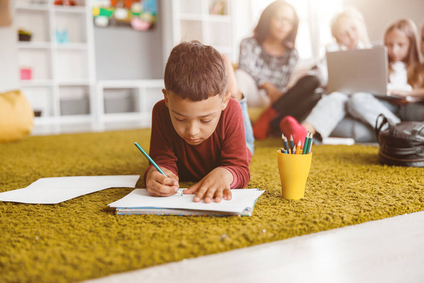 Uczeń trzymający ołówek i rysunek na papierze na podłodze - Zdjęcie, obraz