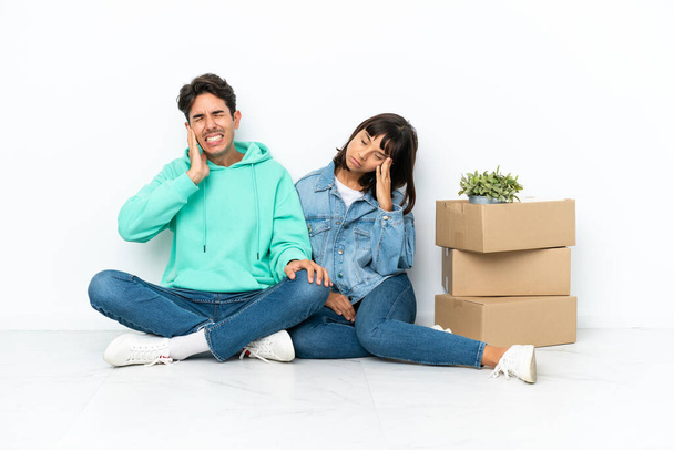Молодая пара делает шаг, поднимая коробку с вещами, сидя на полу изолированы на белом фоне несчастны и разочарованы чем-то - Фото, изображение