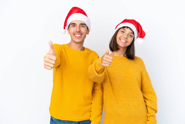 Junges gemischtes Paar feiert Weihnachten isoliert auf weißem Hintergrund und zeigt Daumen hoch, weil etwas Gutes passiert ist - Foto, Bild
