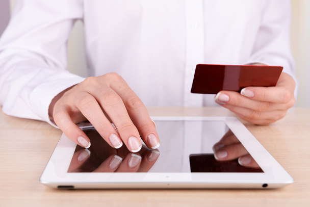 Жіночі руки тримають кредитну картку та комп'ютерний планшет на столі крупним планом
 - Фото, зображення