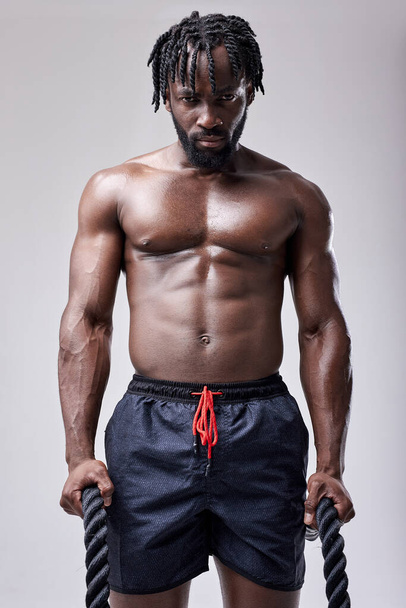 young sexy active african man going to train with battle ropes, keeping fit, isolated - Foto, afbeelding