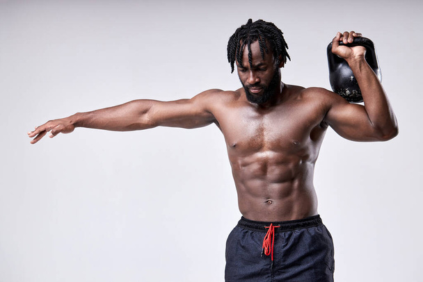 Afro young muscular man training with kettlebell isolated on white background. - Zdjęcie, obraz