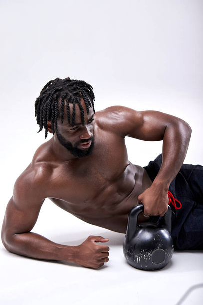 Confident fitness man doing push kettlebell while lying on floor isolated on white - Foto, immagini