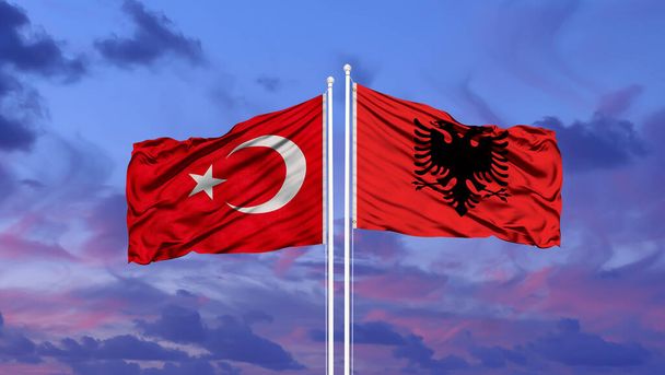 Turkije en Albanië twee vlaggen op vlaggenmasten en blauwe bewolkte lucht - Foto, afbeelding