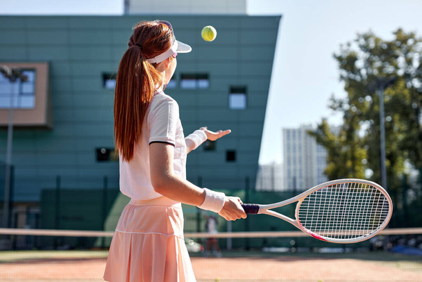 portrait of sporty lady tennis player with racket, raising throwing ball up - Zdjęcie, obraz