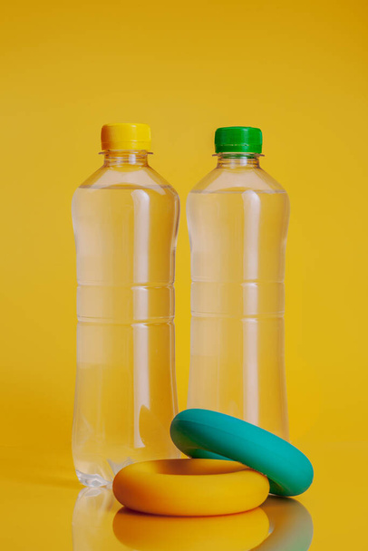 Plastic bottle full of drink on a bright yellow background - Фото, изображение
