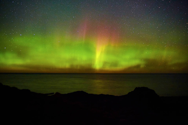 Geceleri karanlık kıyı şeridi ve aurora ışıklarıyla okyanus ve deniz. - Fotoğraf, Görsel