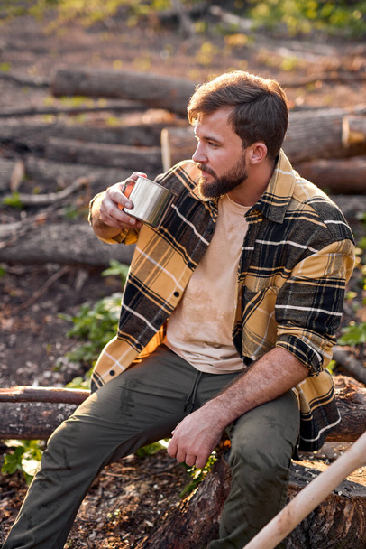 Relaxed male is tired after wood cutting chopping trees, have rest, drink tea - Zdjęcie, obraz