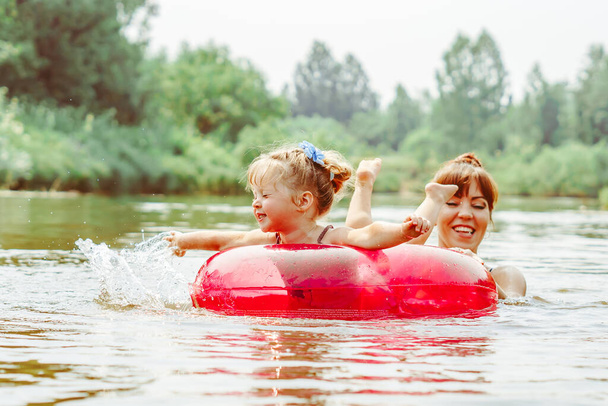 Little sisters having fun swimming in a lake at summer - Zdjęcie, obraz