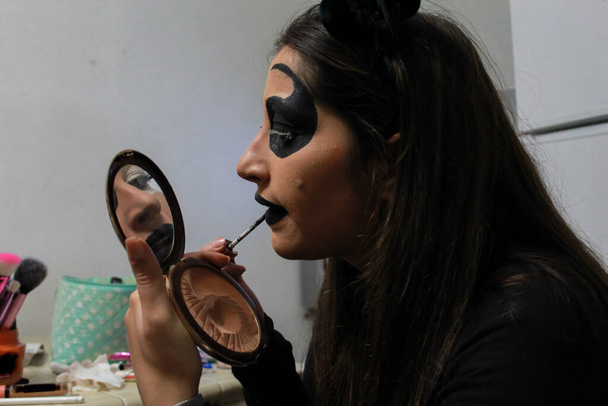 A young Caucasian girl putting on horror makeup for Halloween - Fotografie, Obrázek