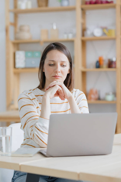 Європейська жінка у своєму домашньому офісі працює з ноутбуком або дивиться веб - сайт - Фото, зображення