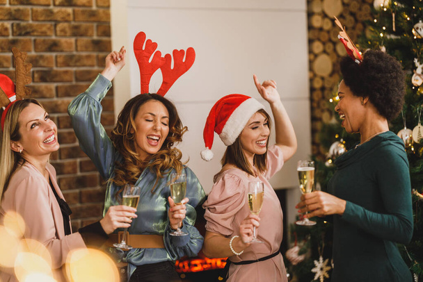 Веселі багатоетнічні дівчата танцюють і розважаються під час тостів з шампанським на новорічній домашній вечірці разом
. - Фото, зображення