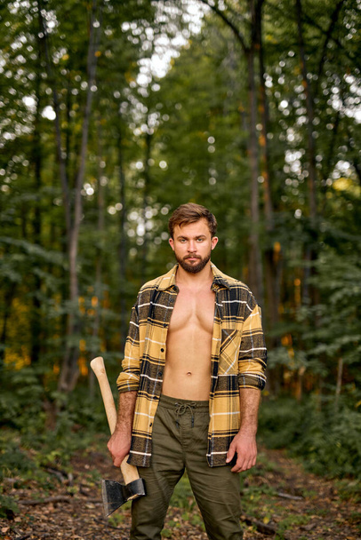 Logging season. Shirtless Lumberman carry axe in forest. Forestry logging. - Photo, image