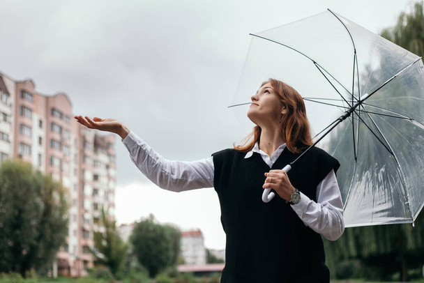 Woman hold transparent umbrella outside wet street autumn near river lake in cloud weather rain park. Lady feel protected from water dripping downpour puddles. Copy space - Foto, Imagem