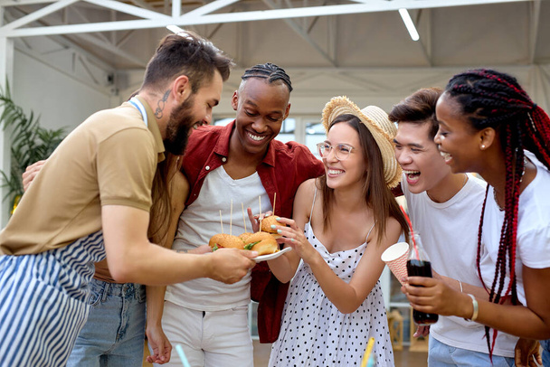 Young people having party in the evening, house patio, eating burgers together - Фото, изображение