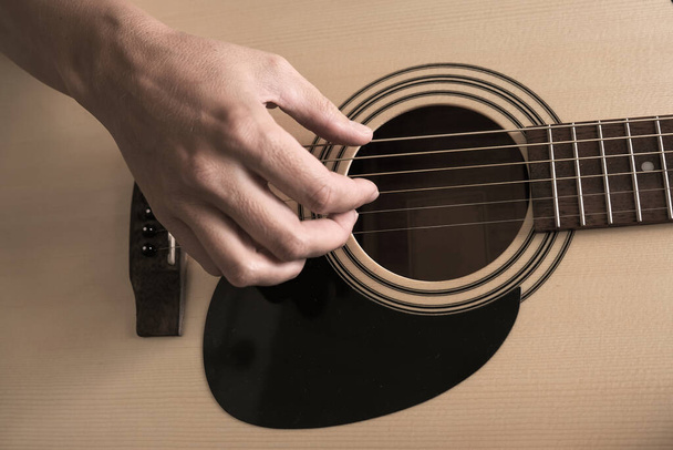 Una mano femenina tocando la guitarra de cerca, autoinstrucción y música jugando concepto tutorial. - Foto, imagen