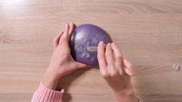 Slime DIY. Female Hands sprinkle glitter on the slime. 4k resolution video. Close up and top view of female hand holding purple shining slime and squeezing it. - Footage, Video