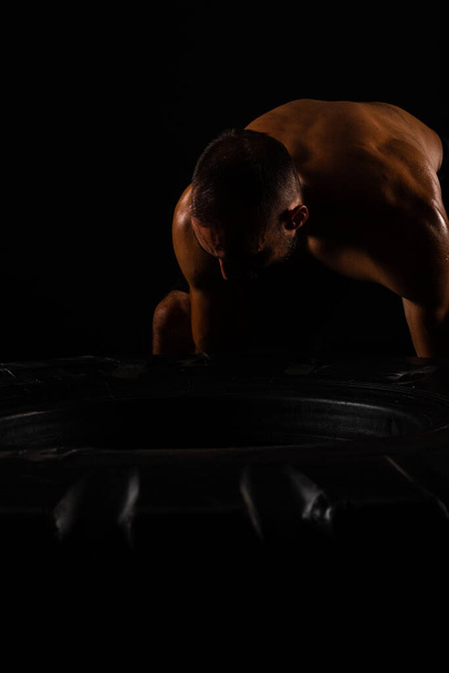 Handsome and topless guy is putting so much effort on the big and heavy training tire - Photo, Image