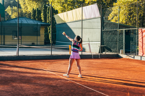 Молода тенісистка служить на глиняному дворі
 - Фото, зображення