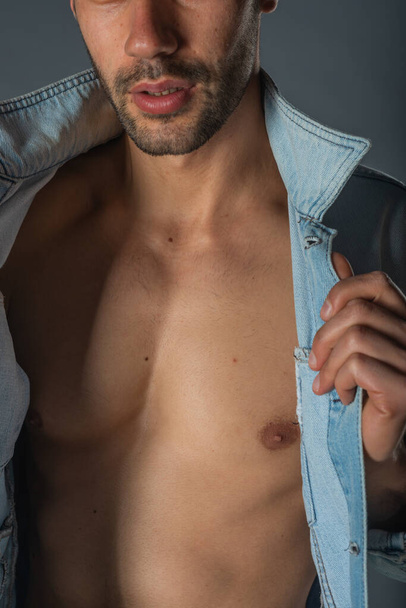 Imagen de un joven macho guapo con abdominales y chaqueta vaquera abierta y jeans. - Foto, imagen