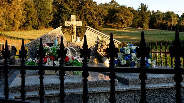 могила с большим количеством пены и крест, охраняемый черной металлической решеткой - Фото, изображение