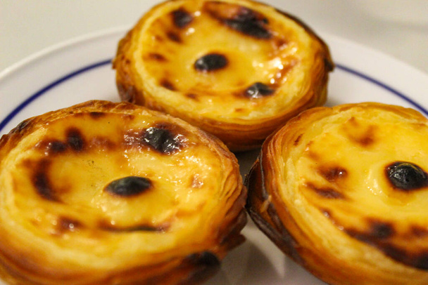 Τυπικές πορτογαλικές πίτες, Pastel de Nata ή Pastel de Belem. Ένα κοντινό πλάνο παραδοσιακών πορτογαλικών αρτοσκευασμάτων κρέμας σε παραδοσιακό caffe - restorant. Ζυμαρικά de nata. Pastis de Belem. - Φωτογραφία, εικόνα