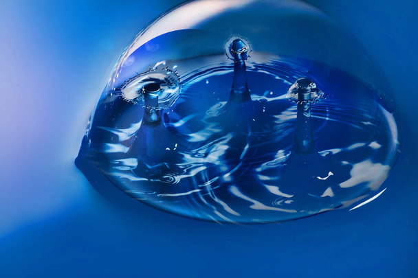 Blaue Oberfläche und Blase mit drei Paaren von Wassertropfen kollidieren - Foto, Bild