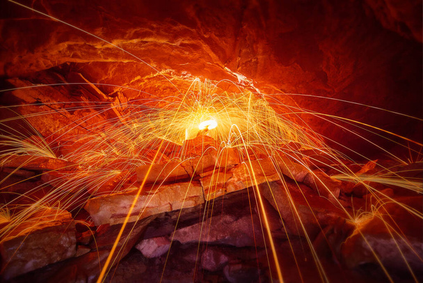 Shower of sparks over stones inside a cave and with a yellow ring of light - Photo, Image