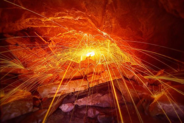 Steel wool sparks in a cave with yellow sparks flowing over stones - Photo, Image