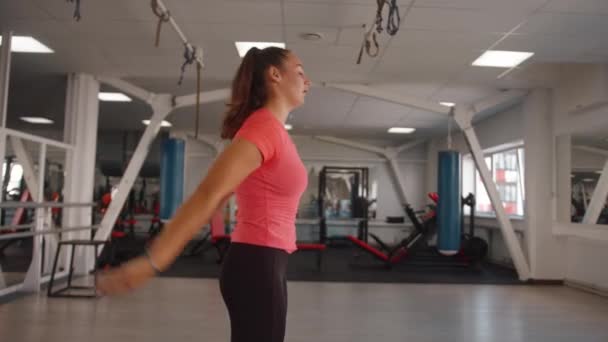 Mladá žena v zpoceném tričku dělá strečink po silovém tréninku v tělocvičně a natahuje záda delta a rotační rameno manžety - Záběry, video