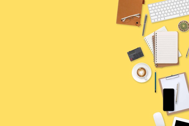 flacher Arbeitstisch mit Laptop, Bürobedarf, Kaffeetasse, Tablet und Mobiltelefon auf farbigem Hintergrund - Foto, Bild