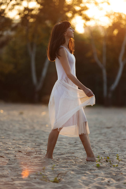 belle jeune femme à la mode en robe élégante marchant à la plage au coucher du soleil
 - Photo, image