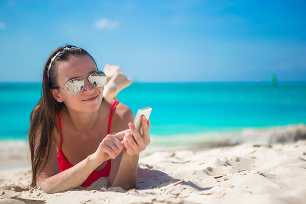 junge Frau mit ihrem Handy am exotischen Strand - Foto, Bild