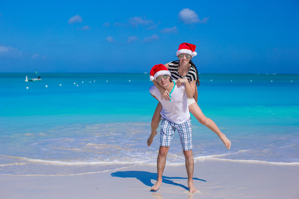 Joven pareja feliz en sombreros rojos de Santa durante sus vacaciones tropicales
 - Foto, imagen