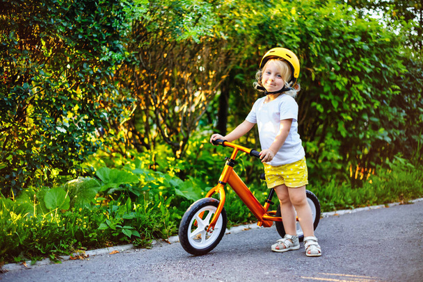 Small children girl with helmets and balance bike outdoors playing - Fotoğraf, Görsel