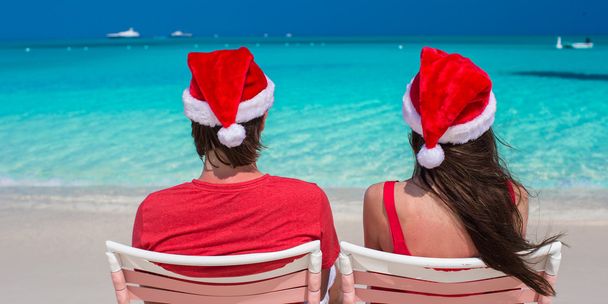 Happy romantic couple in red Santa Hats at tropical beach - Photo, Image
