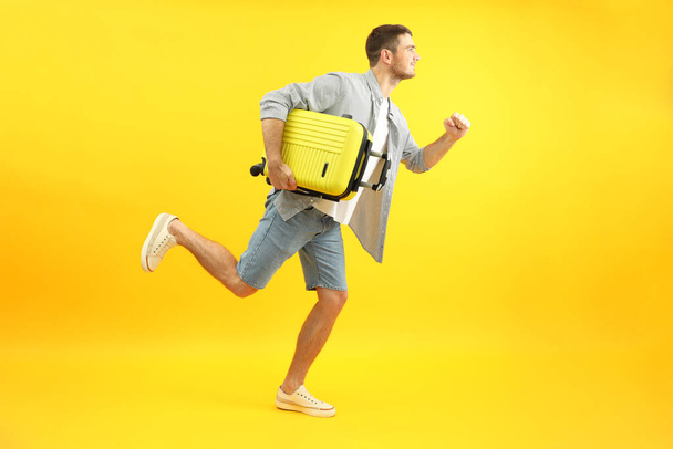 Traveling concept with happy young man on yellow background. - 写真・画像