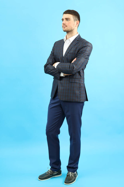 Young businessman in classic suit on blue background. - Foto, Imagen