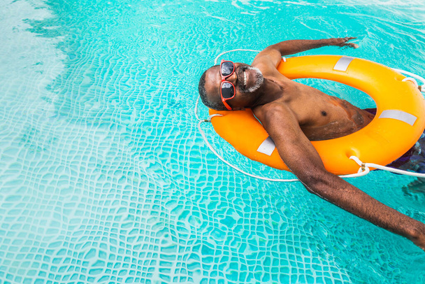 Happy senior man having party in the swimming pool - Active elderly male person sunbathing and relaxing in a private pool during summertime - Фото, изображение