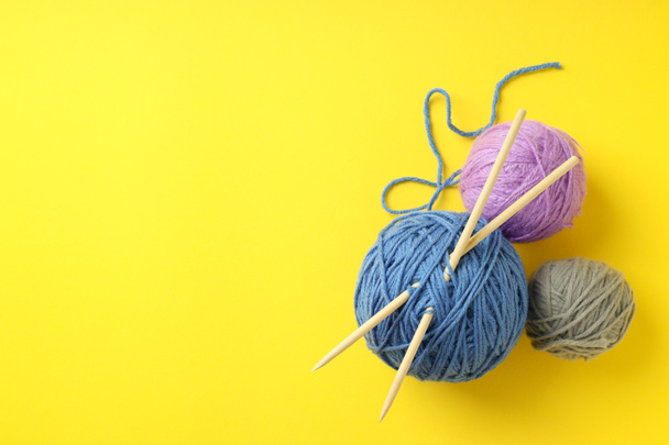 Multi-colored balls of yarn with knitting needles on yellow background. - Photo, Image