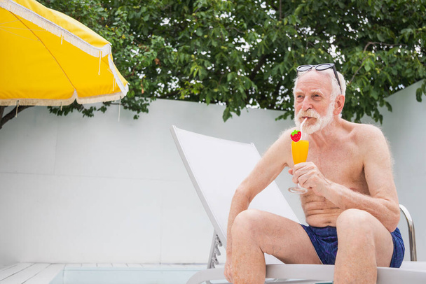 Happy senior man having party in the swimming pool - Active elderly male person sunbathing and relaxing in a private pool during summertime - Zdjęcie, obraz