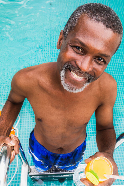 Happy senior man having party in the swimming pool - Active elderly male person sunbathing and relaxing in a private pool during summertime - Fotó, kép