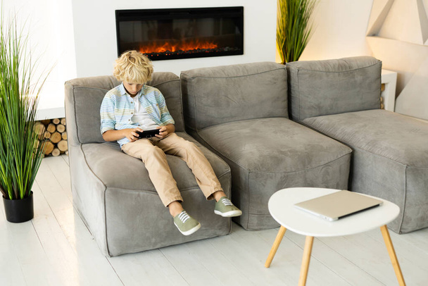Cute boy playing at videogames on the smartphone at home - Foto, Bild