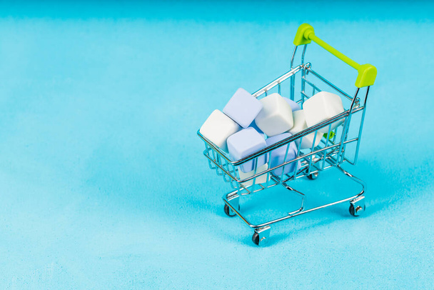 trolley from the supermarket with cubes inside. background blue. after shopping. rash purchases - Foto, imagen
