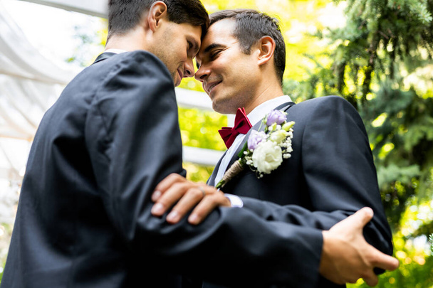 Homoseksueel koppel viert eigen bruiloft - LBGT-koppel tijdens huwelijksceremonie, concepten over inclusiviteit, LGBTQ-gemeenschap en sociale rechtvaardigheid - Foto, afbeelding