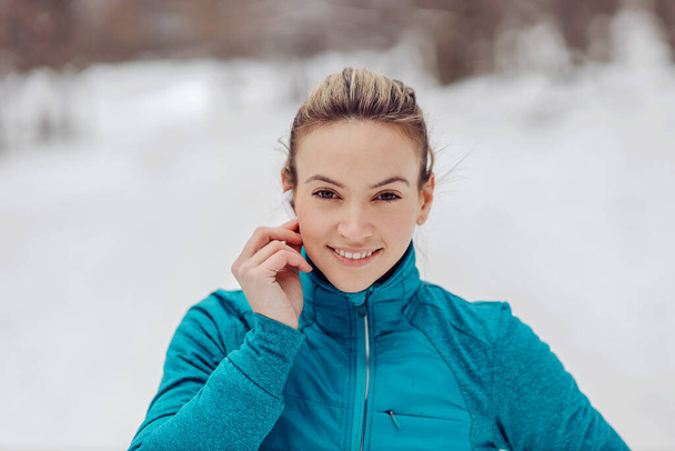 Retrato de deportista poniendo auriculares. Fitness de invierno, vida sana, música, diversión - Foto, Imagen